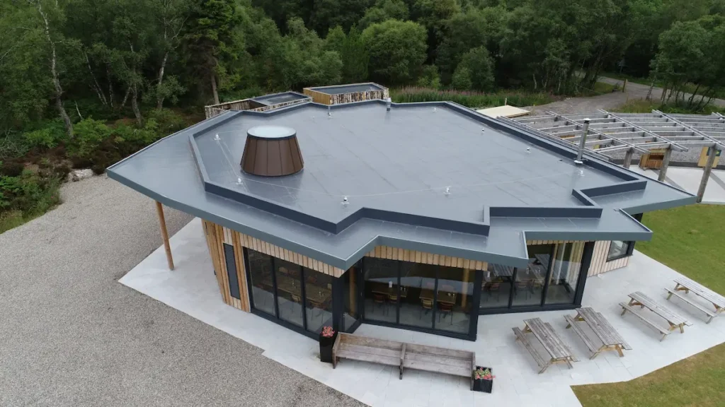 Aerial view of a modern building in Scotland with a geometric roof, large glass facade, and surrounding greenery.